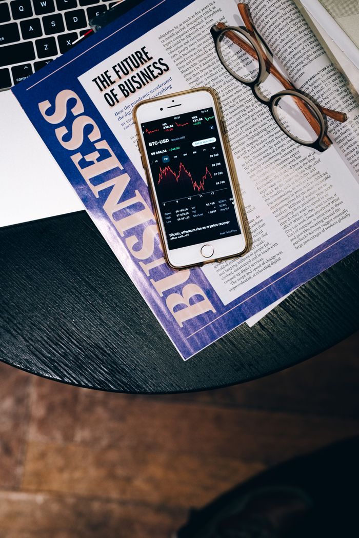 Smartphone displaying stock data on a magazine titled The Future of Business.